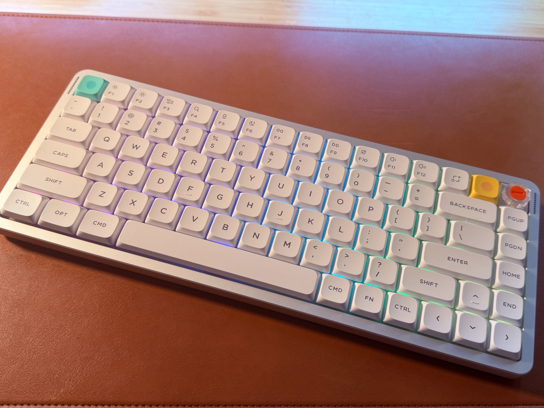A white Nuphy Air75v3 mechanical keyboard with backlit keycaps on a brown leather surface.