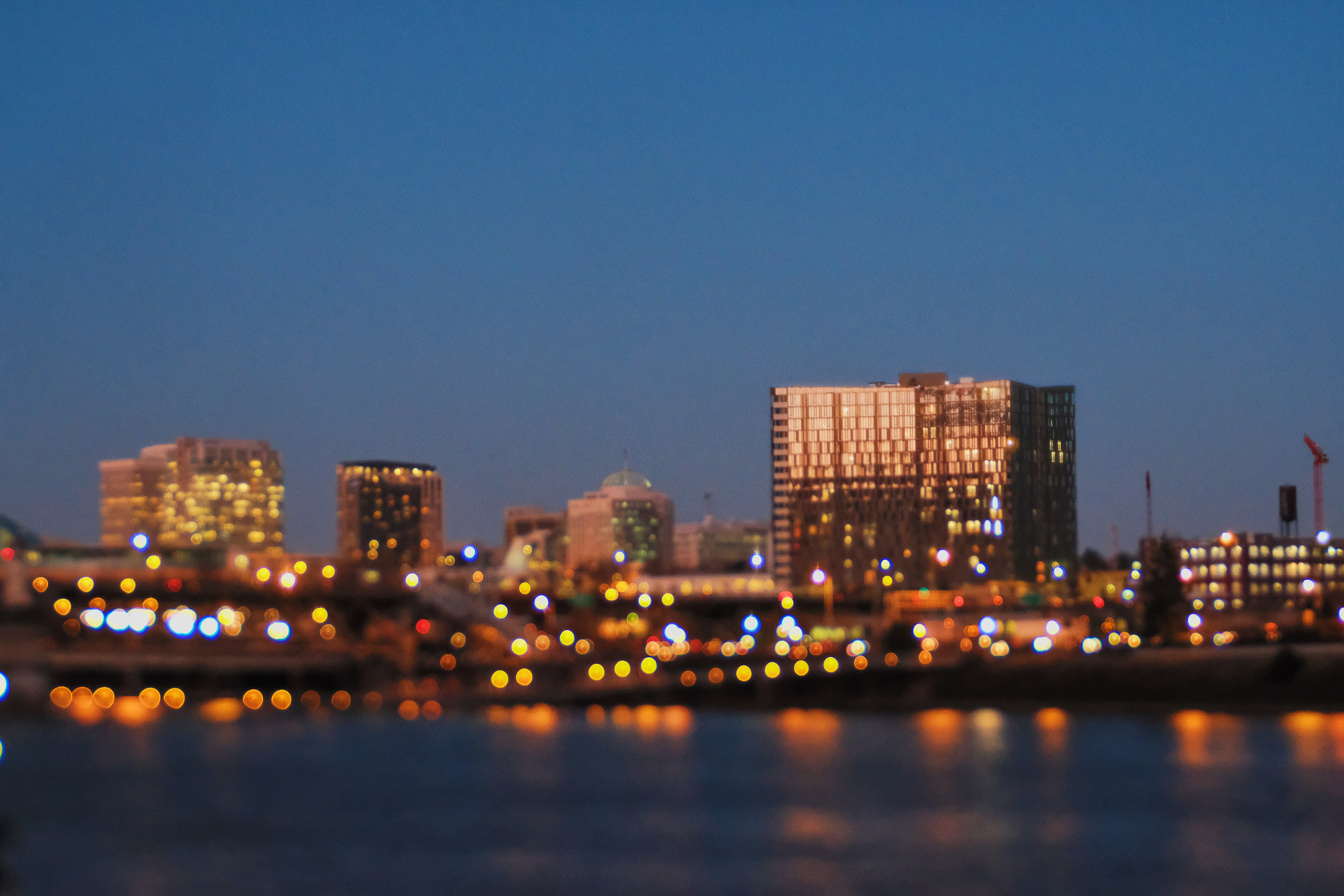 A cityscape is depicted with blurred lights and tall buildings against a twilight sky.